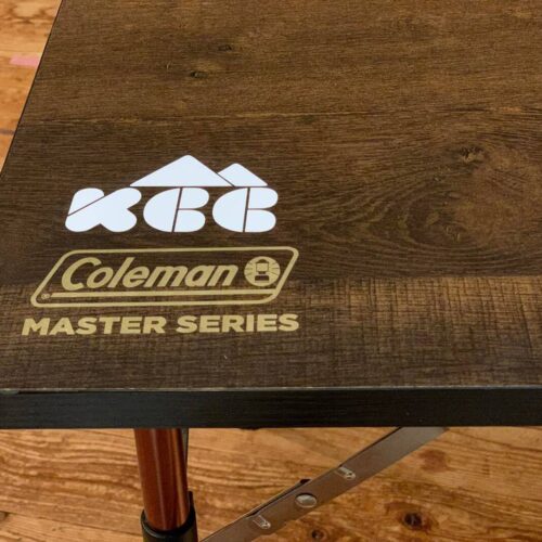コールマンの木製天板のテーブルに貼られたKCC新ロゴ文字抜きステッカー